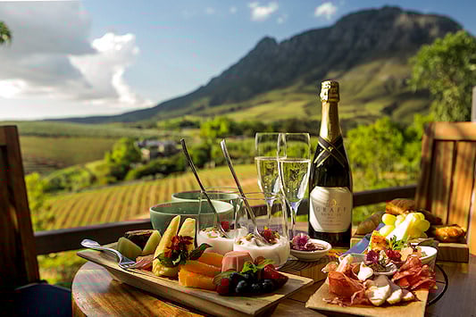 Table set with food and wine overlooking Cape vineyards