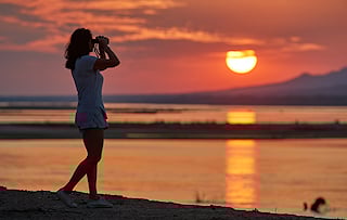 Woman using binoculars at sunset in northern Zimbabwe